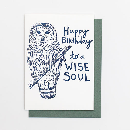 Letterpress greeting card featuring a hand-drawn barred owl printed in a lovely navy ink. The right side of the card says "Happy Birthday to a wise soul!" in a whimsical hand-drawn text, in the same navy ink. The card is white, blank inside, and is paired with a slate grey envelope.
