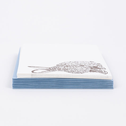 Set of 10 Letterpress Note Cards featuring a hand-drawn Cottontail Rabbit letterpress printed in a warm brown ink onto 100% cotton paper. Includes 10 baby blue envelopes. Size A6. The cards are stacked on the envelopes shown on a white background. Image is a side-view.