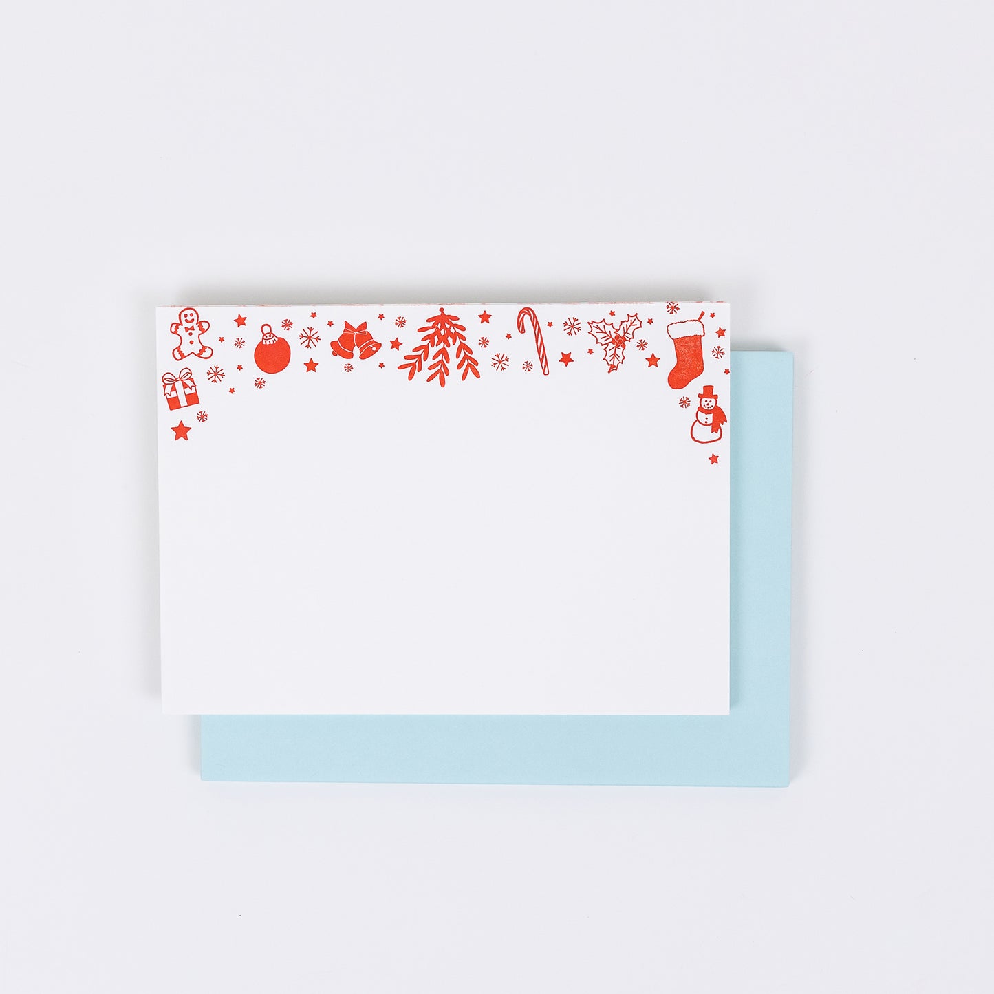 Set of 10 letterpress holiday note cards featuring hand-drawn icons like gingerbread men, stockings, snowflakes, and a snowman, printed in bright red ink on white 100% cotton paper. Includes 10 soft light blue envelopes. A6 size.