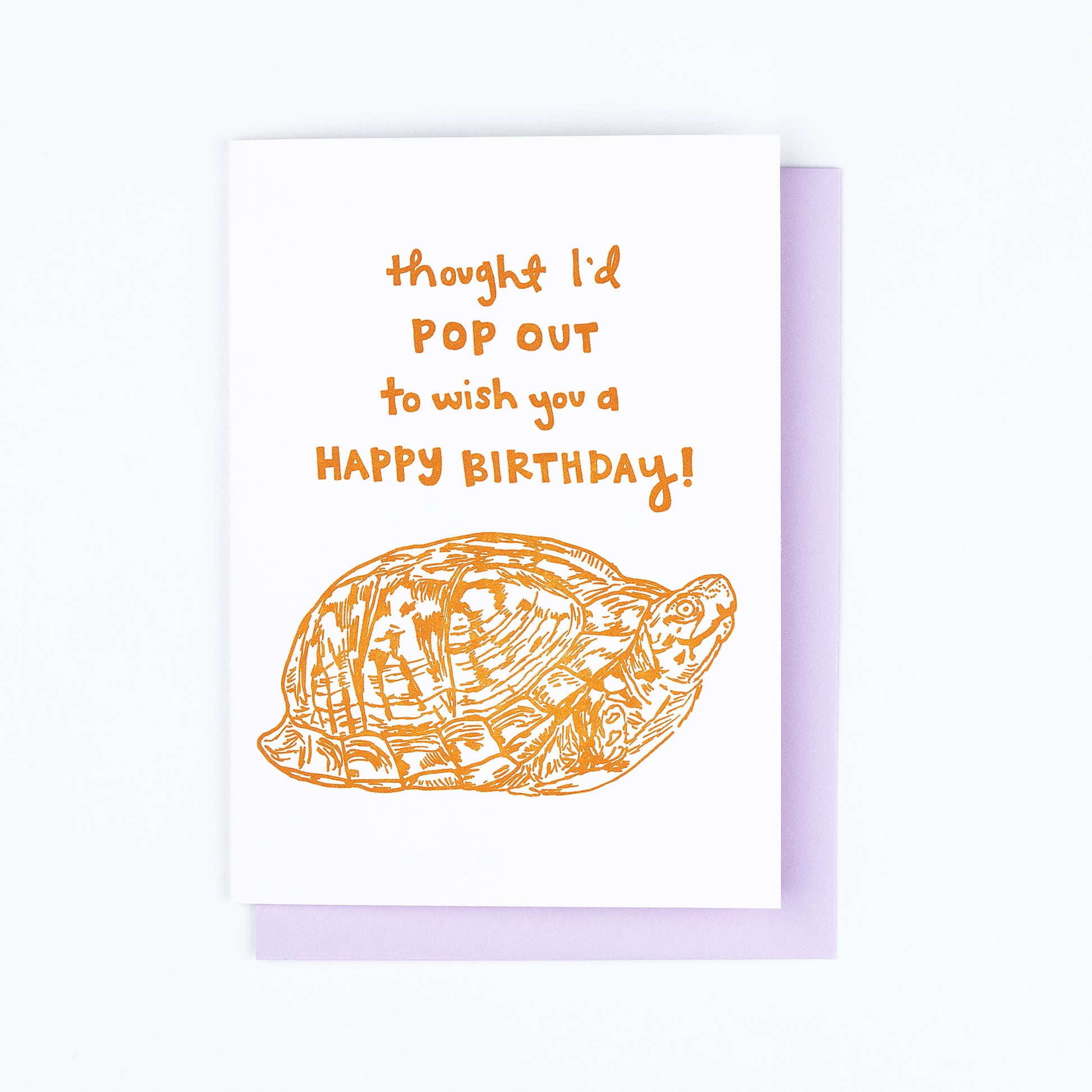 Letterpress greeting card featuring a hand-drawn Appalachian Box Turtle printed in a vibrant dark orange ink. "Thought I'd pop out to wish you a Happy Birthday!" is written on the top of the card in a whimsical hand-drawn text, in the same orange ink. The card is white, blank inside, and is paired with a lilac purple envelope.