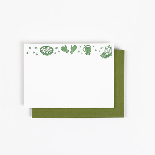 Set of 10 letterpress holiday note cards featuring hand-drawn cozy icons like a pie, mittens, cup, and boots, printed in dark green ink on 100% cotton paper. Includes 10 dark green envelopes. A6 size.