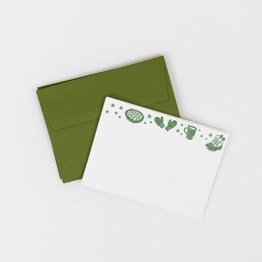 Set of 10 letterpress holiday note cards featuring hand-drawn cozy icons like a pie, mittens, cup, and boots, printed in dark green ink on 100% cotton paper. Includes 10 dark green envelopes. A6 size.