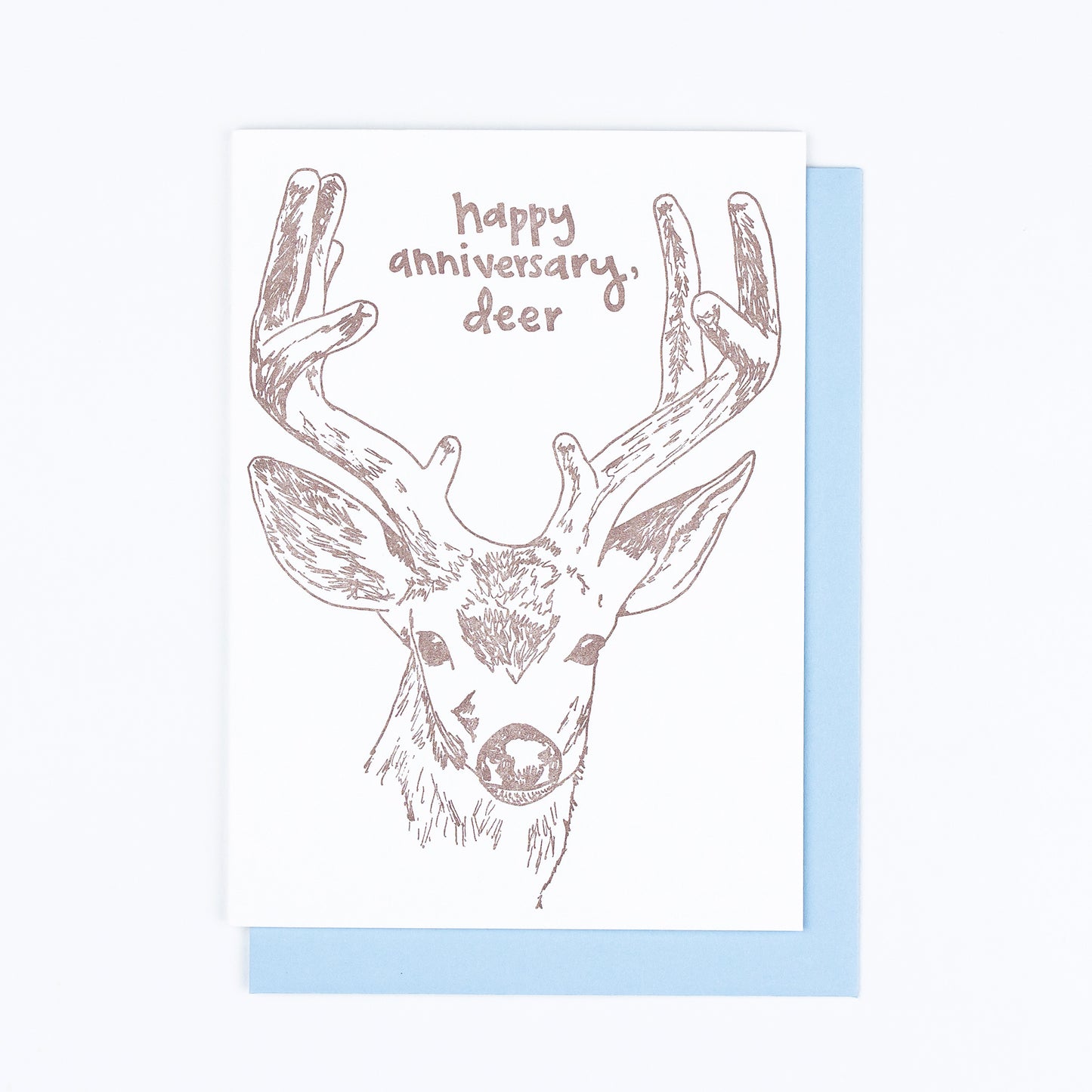 Letterpress greeting card featuring a hand-drawn buck, printed in an earthy brown ink. Whimsical hand-drawn text saying "Happy Annivesary, Deer" is shown inside the deer antlers, in the same brown ink. The card is white, blank inside, and is paired with a light blue envelope.