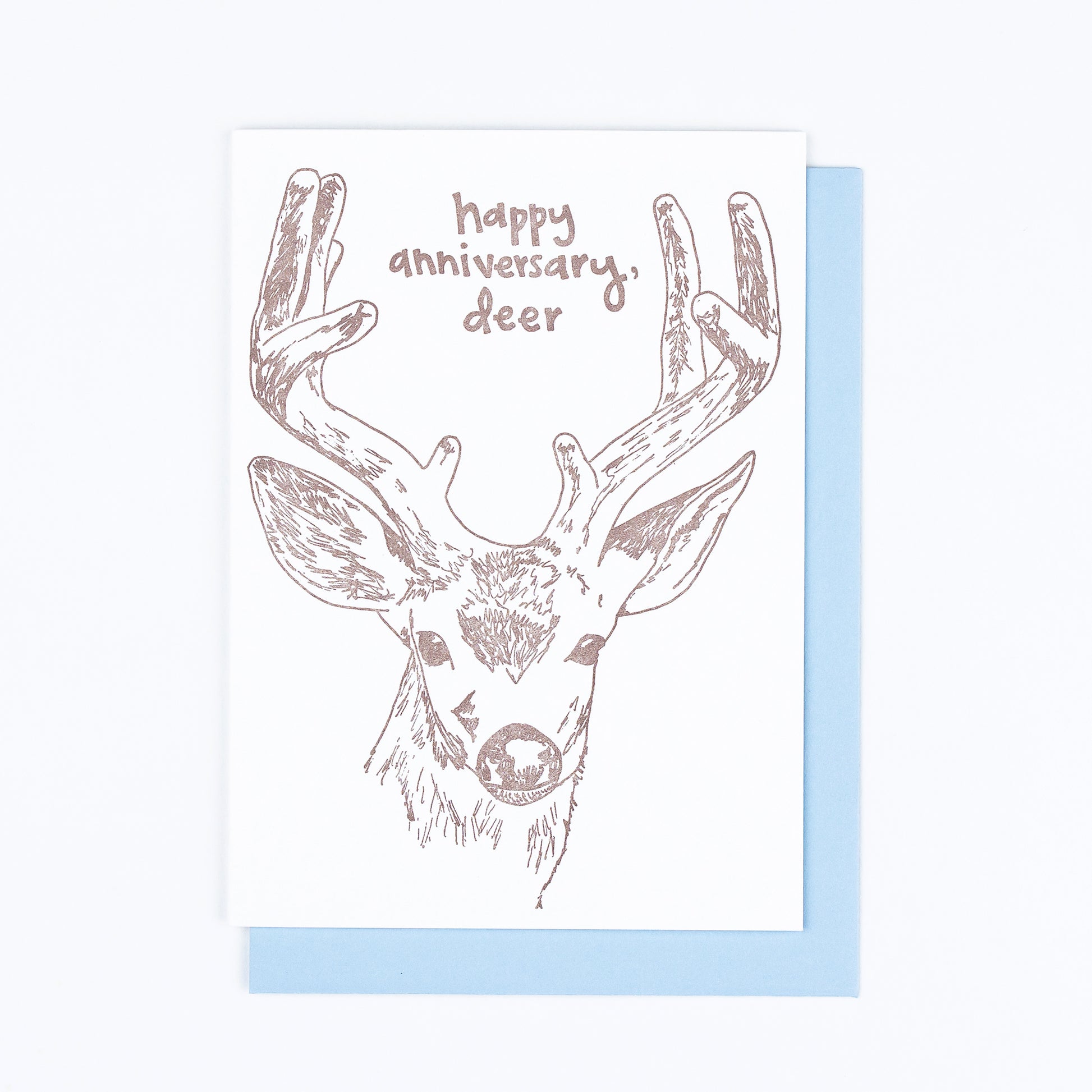 Letterpress greeting card featuring a hand-drawn buck, printed in an earthy brown ink. Whimsical hand-drawn text saying "Happy Annivesary, Deer" is shown inside the deer antlers, in the same brown ink. The card is white, blank inside, and is paired with a light blue envelope.