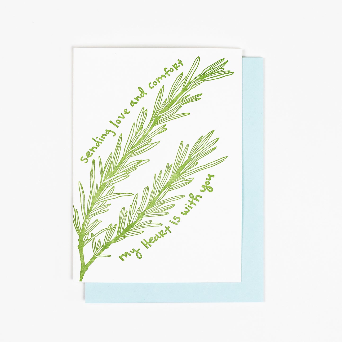Letterpress greeting card featuring an intricate hand-drawn rosemary herb sprig, printed in a rich sage green ink. Whimsical hand-drawn text saying "Sending love and comfort. My heart is with you." is printed in the same green ink. The card is white, blank inside, and is paired with a light blue envelope.