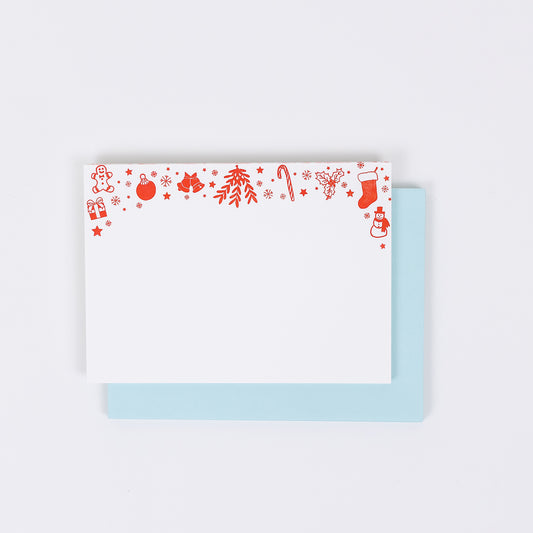 Set of 10 letterpress holiday note cards featuring hand-drawn icons like gingerbread men, stockings, snowflakes, and a snowman, printed in bright red ink on white 100% cotton paper. Includes 10 soft light blue envelopes. A6 size.