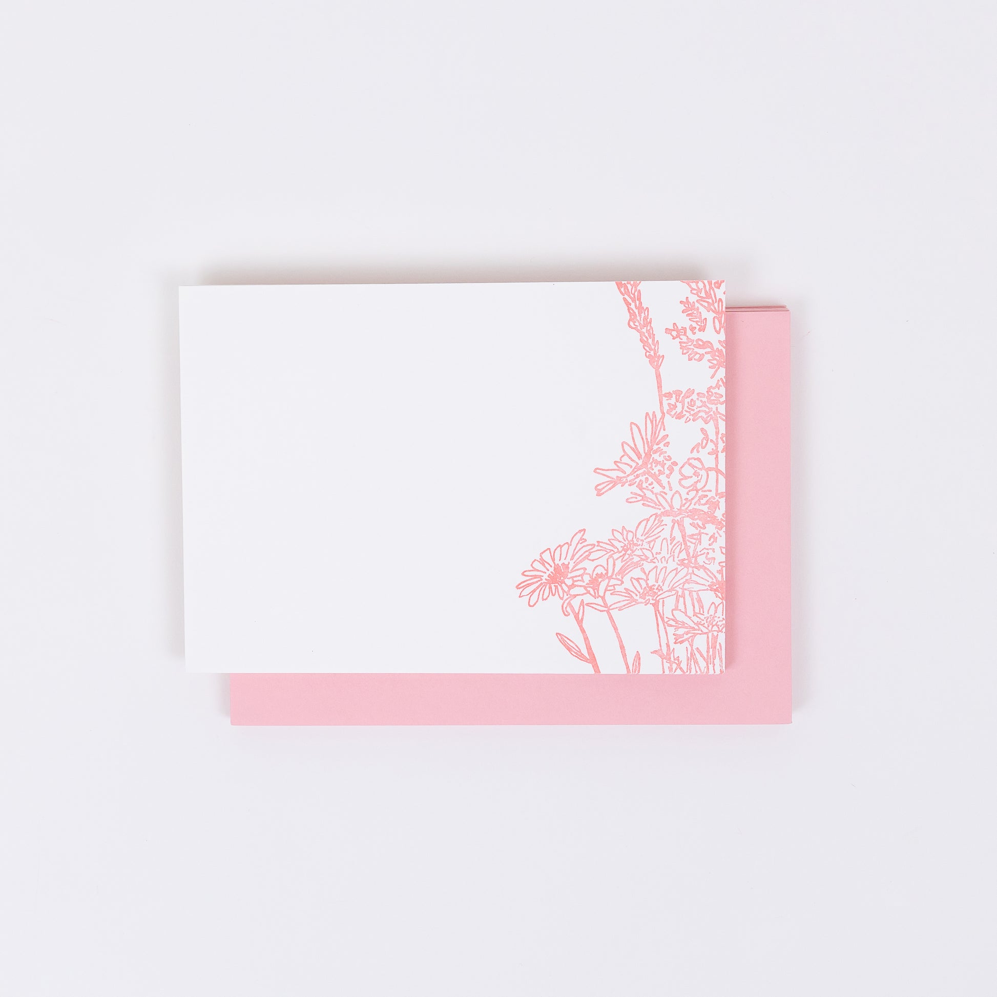 Set of 10 Letterpress Note Cards featuring a hand-drawn Wildflower Bouquet letterpress printed in a soft pink ink onto 100% cotton paper. Includes 10 soft pink envelopes. Size A6.  The cards are stacked on the envelopes shown on a white background.