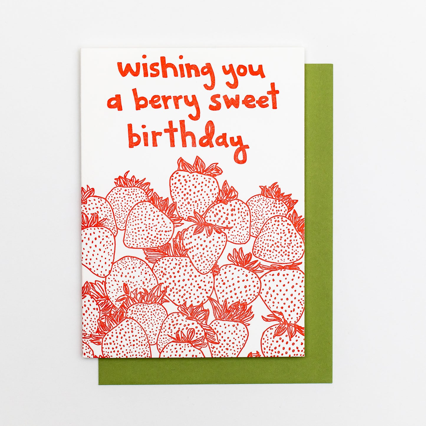 Letterpress greeting card featuring hand-drawn strawberries printed in a vibrant red ink. "Wishing you a Berry Sweet Birthday!" is written at the top of the card in a whimsical hand-drawn text, printed in the same red ink. The card is white, blank inside, and is paired with a deep green envelope.