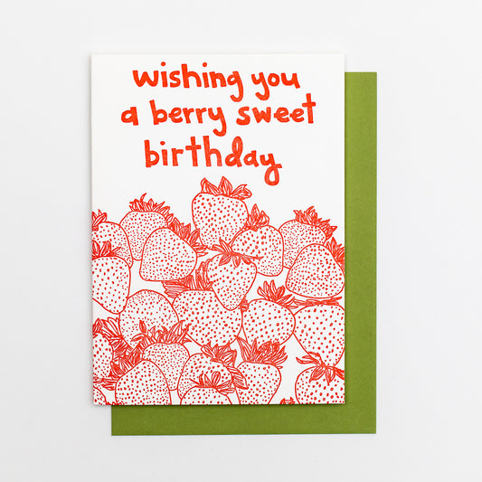 Letterpress greeting card featuring hand-drawn strawberries printed in a vibrant red ink. "Wishing you a Berry Sweet Birthday!" is written at the top of the card in a whimsical hand-drawn text, printed in the same red ink. The card is white, blank inside, and is paired with a deep green envelope.