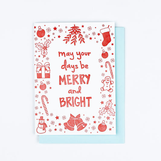 Letterpress greeting card featuring a hand-drawn Holiday Icons printed in a vibrant red ink. "May your days be Merry & Bright!" is printed in a whimsical hand-drawn text, in the same red ink. The card is white, blank inside, and is paired with a sky blue envelope.