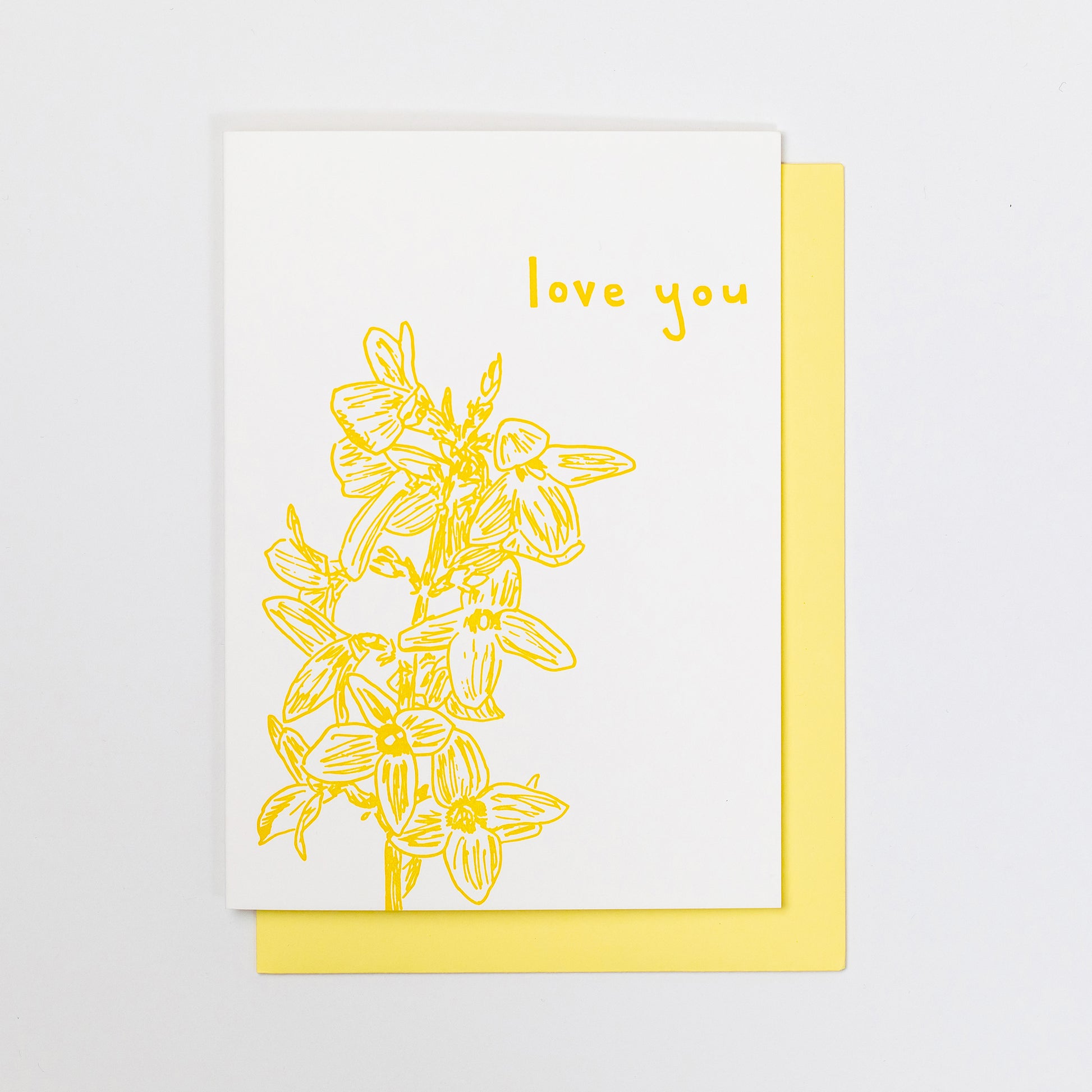 Letterpress greeting card featuring hand-drawn forsythia branches, printed in an vibrant golden ink. Whimsical hand-drawn text saying "Love You" is shown on the top right corner of the card, in the same vibrant golden ink. The card is white, blank inside, and is paired with a light yellow envelope.