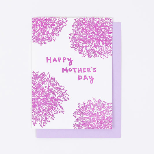 Letterpress greeting card featuring hand-drawn Dahlia flowers, printed in a vibrant dark fuchsia ink. The top center of the card says "Happy Mother's Day" in a whimsical hand-drawn text, in the same dark fuchsia ink. The card is white, blank inside, and is paired with a lilac purple envelope.