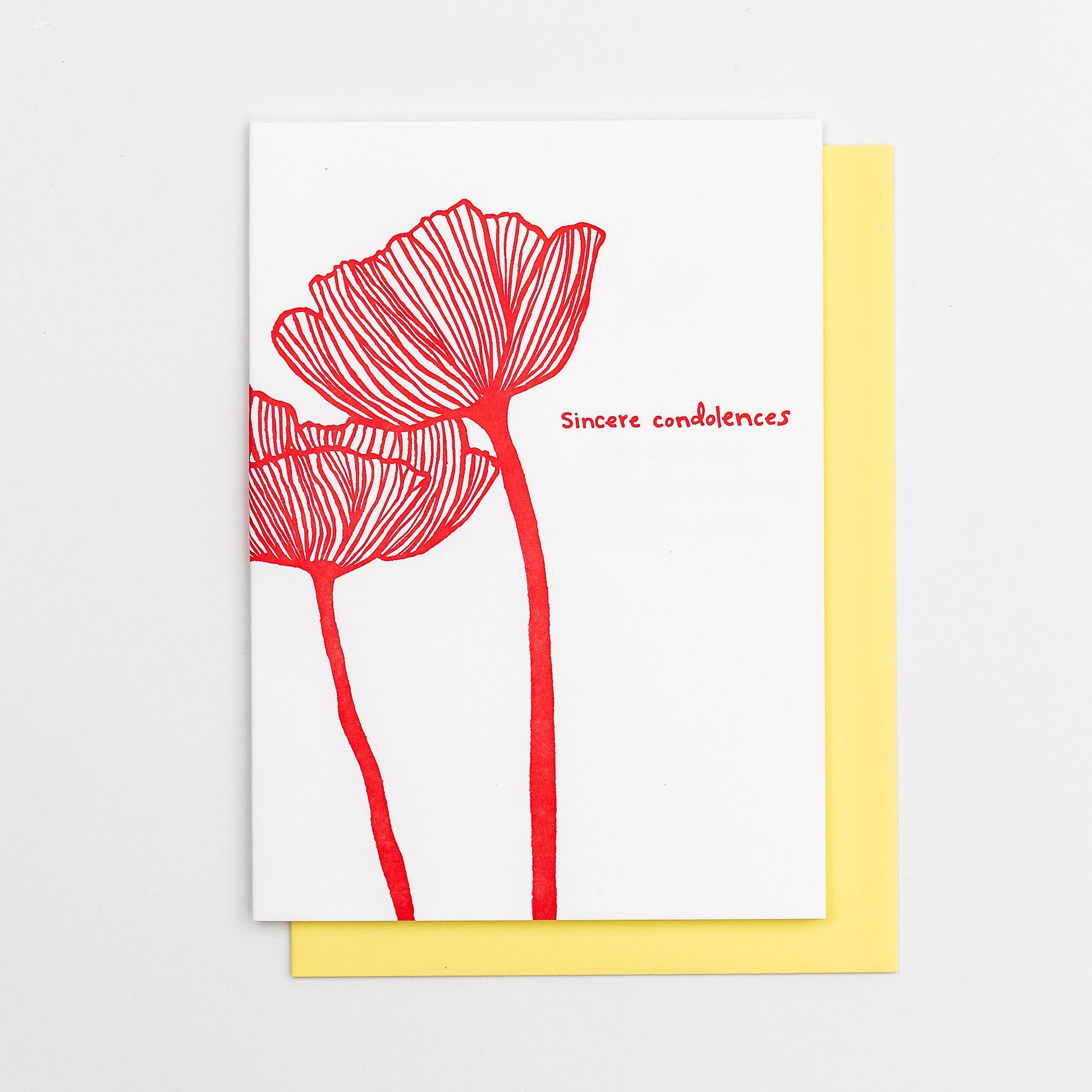 Letterpress greeting card featuring an intricate hand-drawn poppy flower, printed in a vibrant red ink ink. Whimsical hand-drawn text saying "Sincere Condolences" is shown on the right of the card, in the same red ink. The card is white, blank inside, and is paired with a soft yellow envelope.