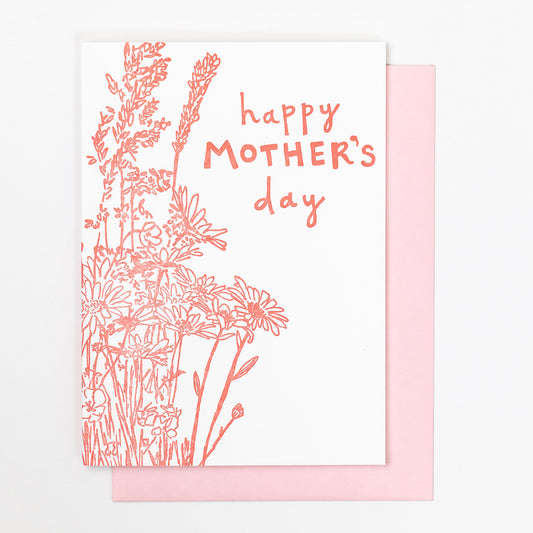 Letterpress greeting card featuring a hand-drawn  wildflower bouquet, printed in a vibrant pink ink. The top center of the card says "Happy Mother's Day" in a whimsical hand-drawn text, in the same pink ink. The card is white, blank inside, and is paired with a light pink envelope.